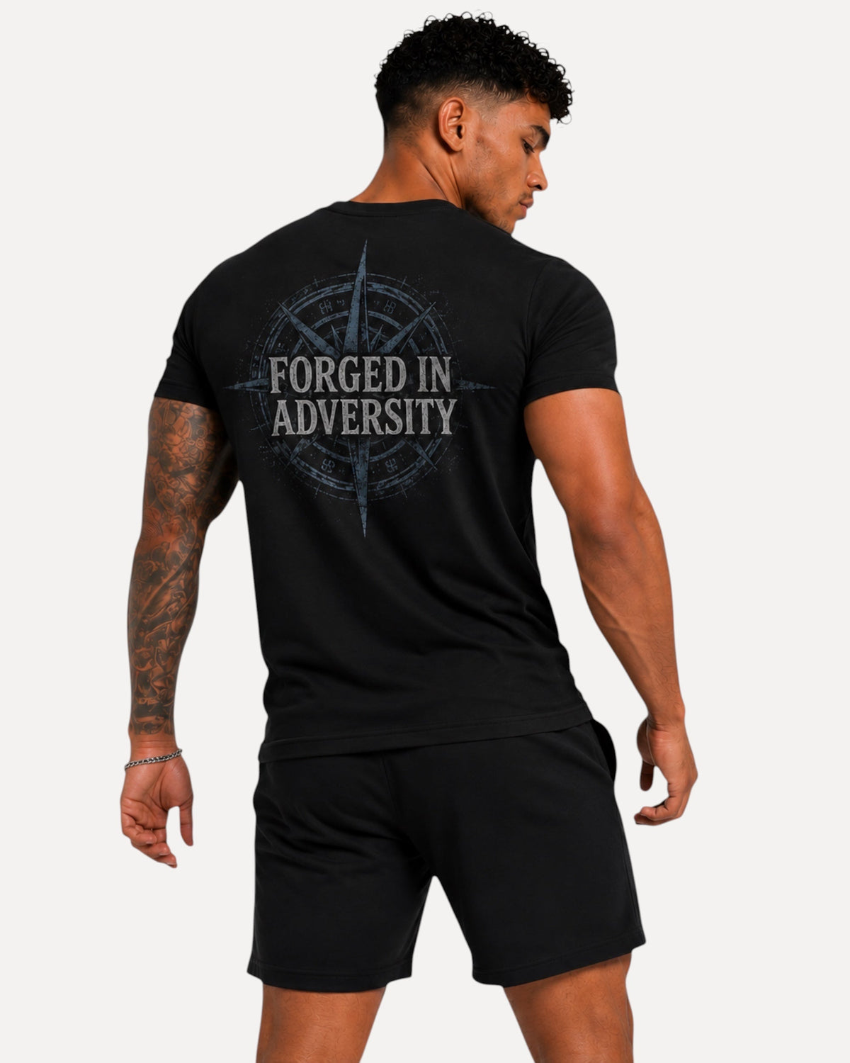 My Store Athlex black athletic t-shirt featuring a Forged in Adversity compass graphic on the back worn by a man