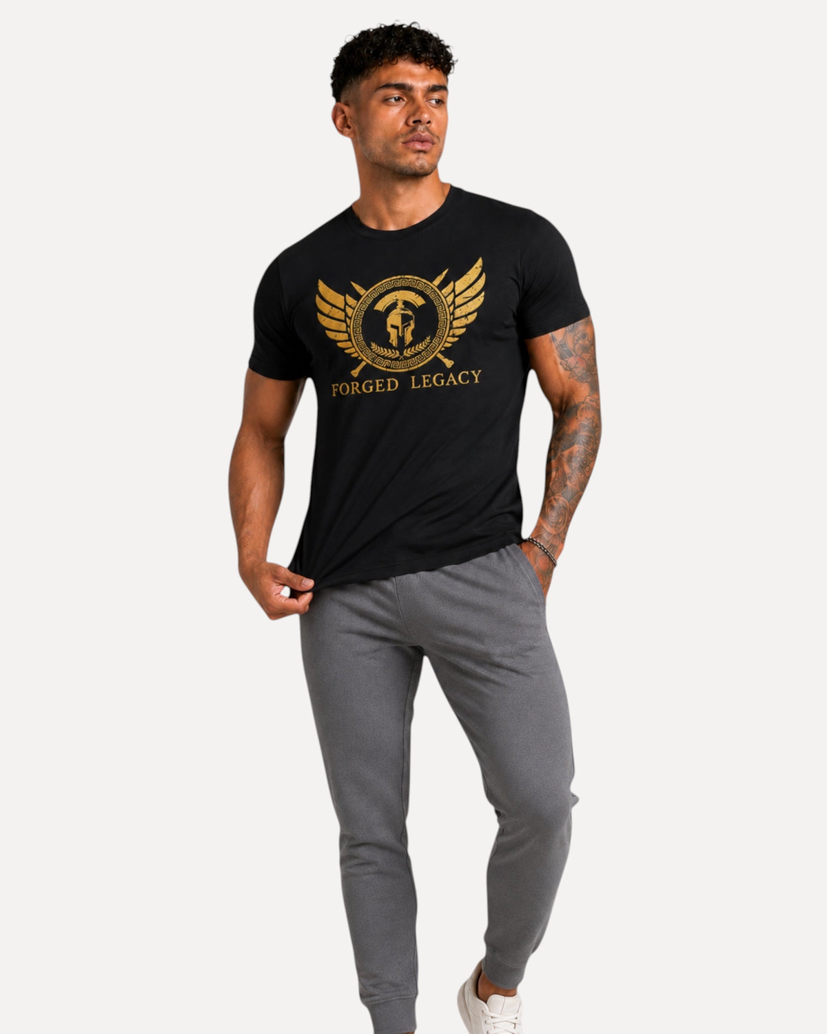 My Store ATHLEX Forged Legacy black cotton tee with gold warrior emblem graphic worn by a man in grey joggers