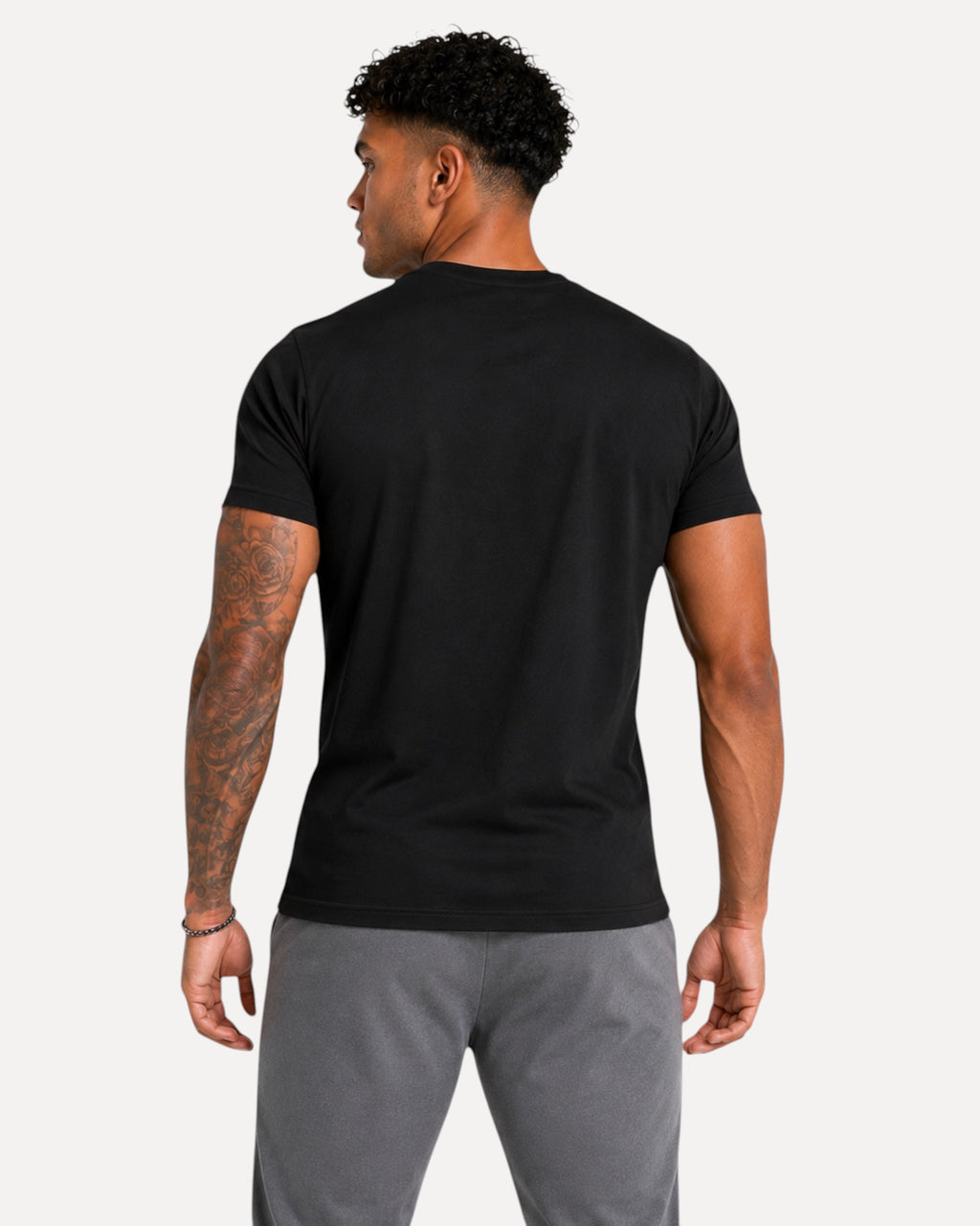 Back view of a man wearing a plain black My Store ATHLEX Phantom Skull cotton tee with grey athletic shorts